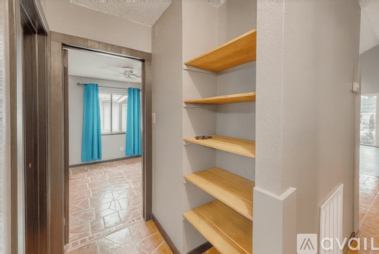 A hallway with a wooden staircase and a glass door leading to a room with blue curtains.
