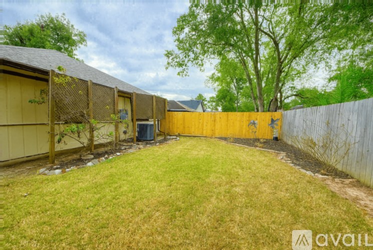 A backyard with a fence, a shed, and a tree.