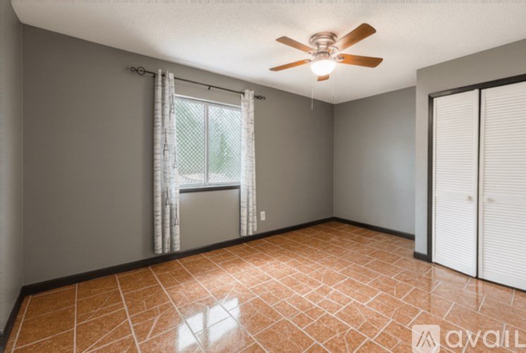 A room with a ceiling fan and a window with curtains.