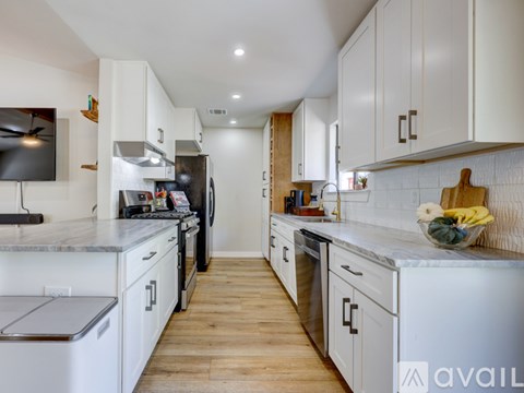 A modern kitchen with white cabinets and wooden floors.