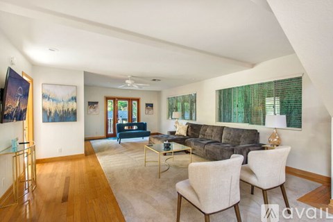 A living room with a grey couch and a painting on the wall.