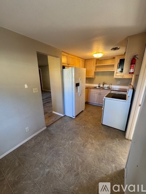 A kitchen with a refrigerator, sink, and cabinets.