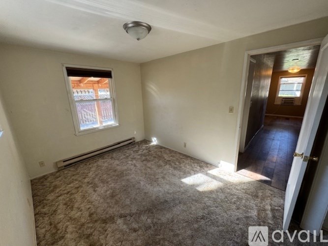 A room with a carpeted floor, a window, and a door.