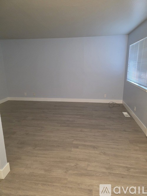 A room with wooden flooring and a window with blinds.