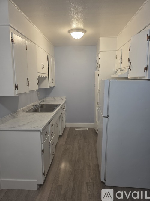 A kitchen with white cabinets and a white fridge.