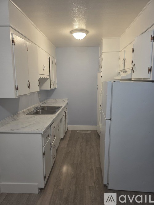 A kitchen with white cabinets and a white fridge.
