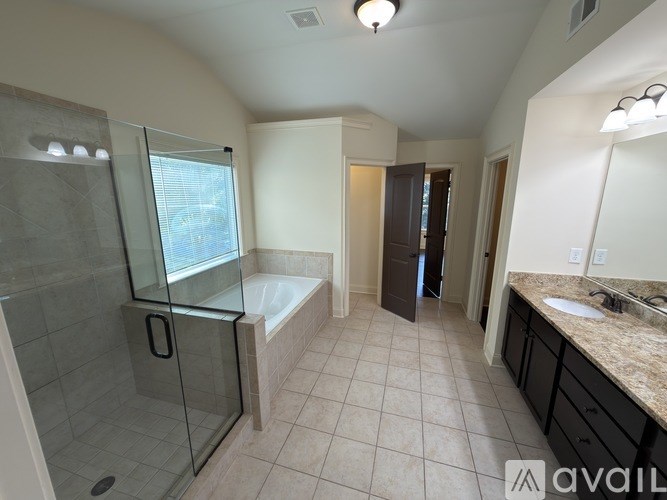 A bathroom with a glass shower door and a bathtub.