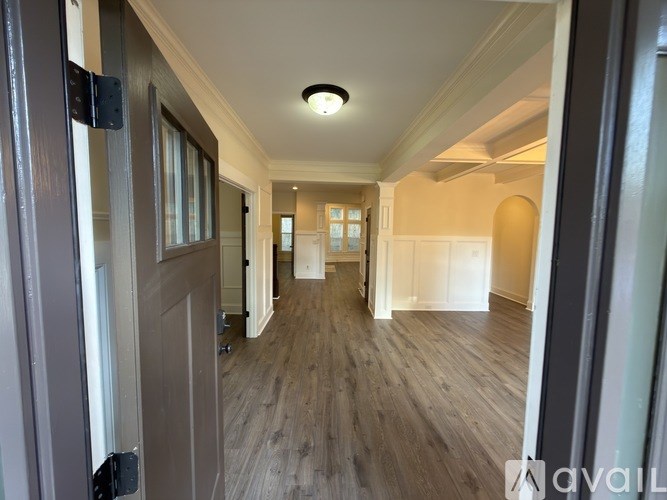 A hallway with wooden floors and white walls.