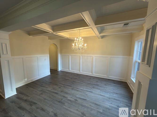 A spacious room with wooden flooring and a chandelier.
