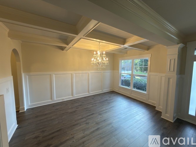 A large empty room with wooden floors and a chandelier.