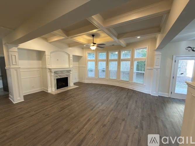 A spacious room with wooden floors and a fireplace.