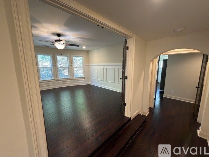A spacious room with wood flooring and a ceiling fan.