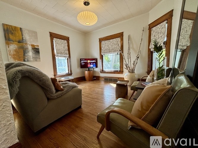 A living room with a grey couch, a brown armchair, and a TV mounted on the wall.