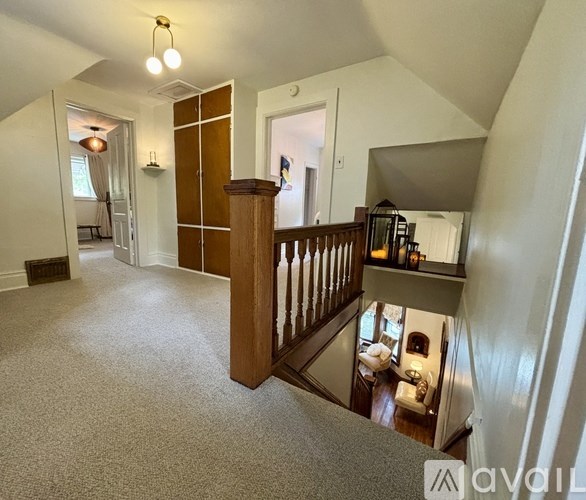 A living room with a carpeted floor and a wooden staircase.