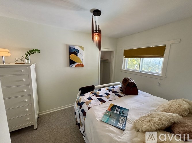 A bedroom with a bed, a dresser, and a painting on the wall.