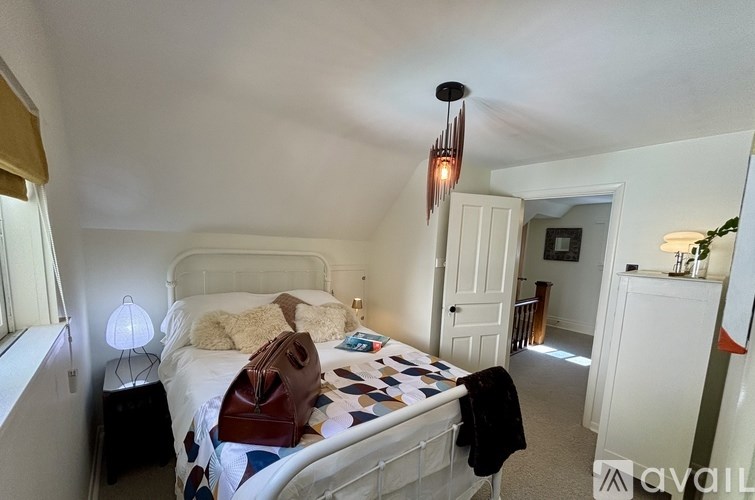 A bedroom with a bed, a lamp, a teddy bear, and a chandelier.