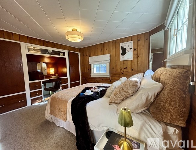 A bedroom with a bed, a chair, and a lamp.