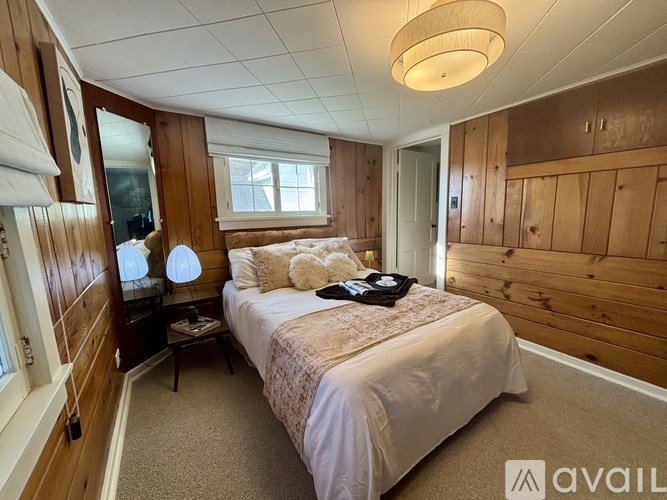 A bedroom with a bed, nightstand, and a window.