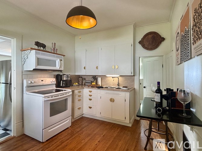 A kitchen with white appliances and wooden floors.