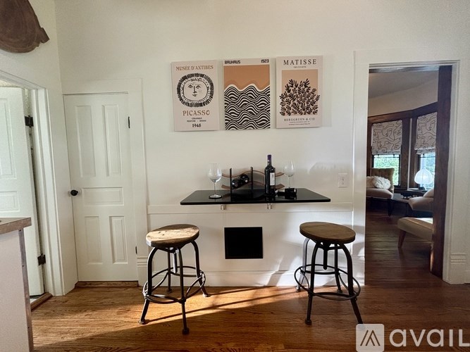 A kitchen with a bar stool and a framed picture of a wine glass.