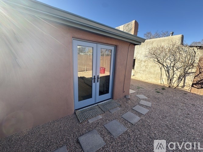 A small house with a glass door and a stone pathway leading to it.