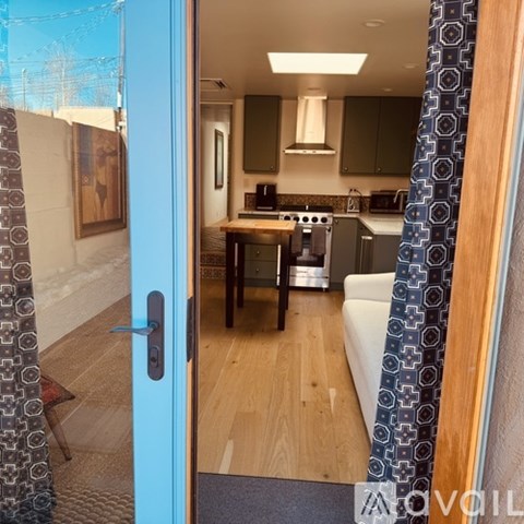 A kitchen with a table and chairs is visible through a doorway.