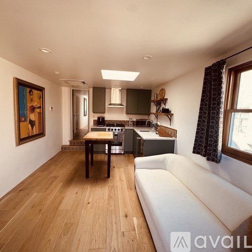 A modern kitchen with wooden floors and a white sofa.