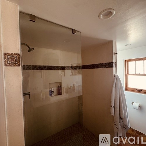 A bathroom with a glass shower stall and a towel hanging on the door.