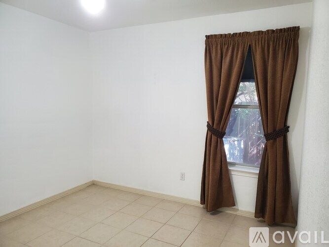 A room with a window and brown curtains.