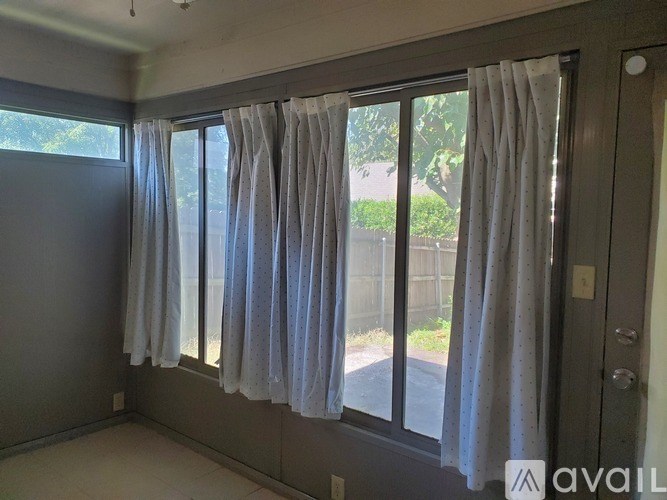 A room with a window covered by white curtains.