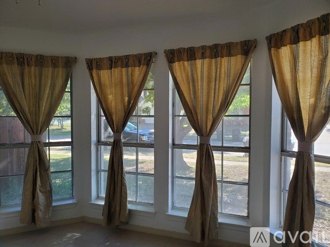 A room with three windows covered by tan curtains.