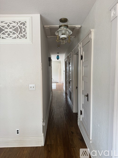 A long hallway with white walls and wood floors.