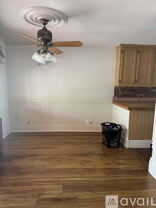 A room with a ceiling fan and wooden flooring.