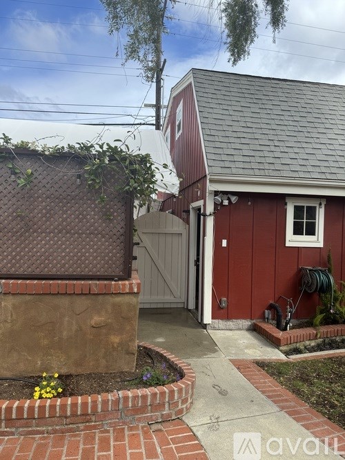 A red house with a grey roof and a brown fence.