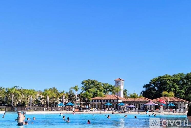 A sunny day at the pool with people swimming and a building in the background.
