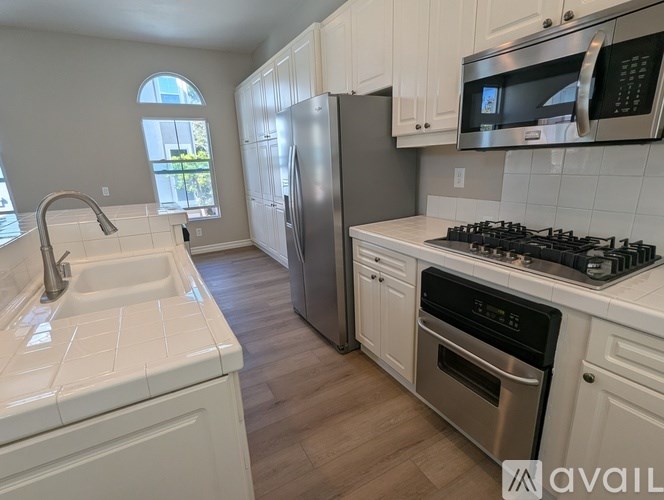 A kitchen with white cabinets and a stainless steel refrigerator.