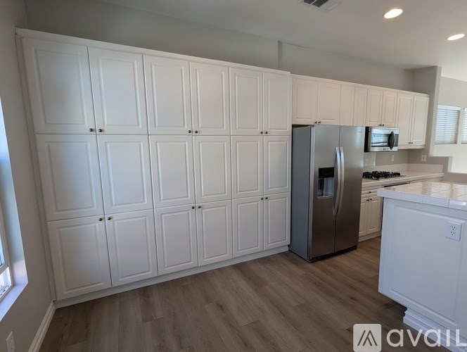 A kitchen with white cabinets and a stainless steel refrigerator.