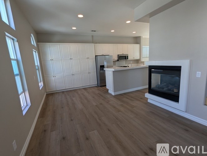 A modern kitchen with a white fireplace and wooden flooring.