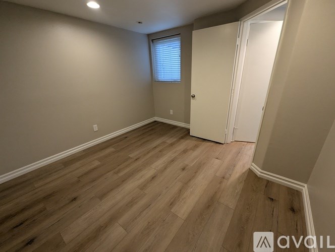 A room with wooden flooring and a window with blinds.