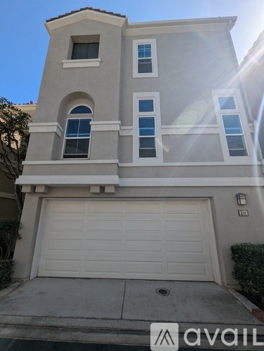 A two-story house with a garage door and a balcony.