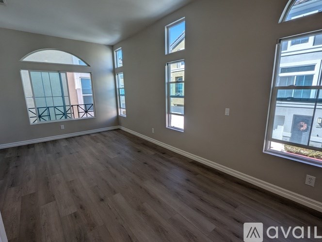 A room with wooden flooring and large windows overlooking a cityscape.