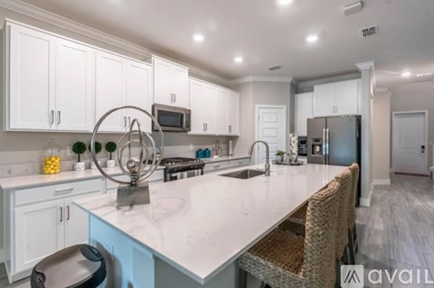 A modern kitchen with white cabinets and a marble countertop.