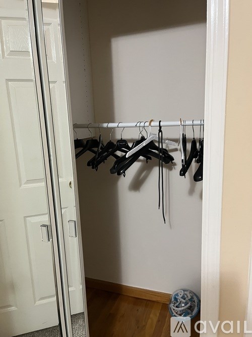 A white closet with clothes hanging on a rail.