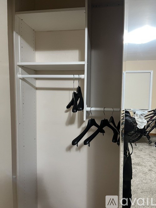 A white closet with clothes hanging on hangers.