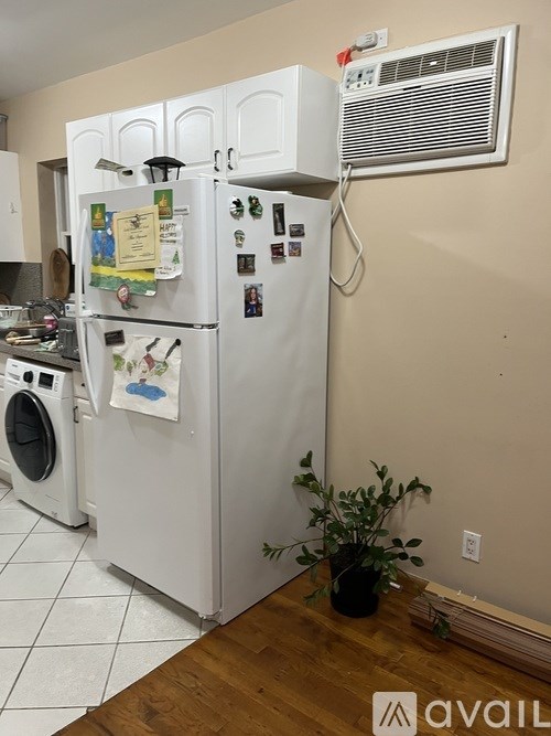 A white fridge with a potted plant in front of it.