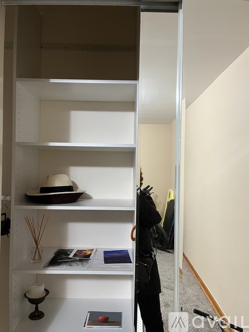 A hat is sitting on the second shelf from the top.