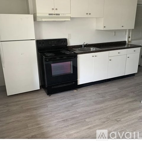 A black oven in a kitchen with white cabinets.