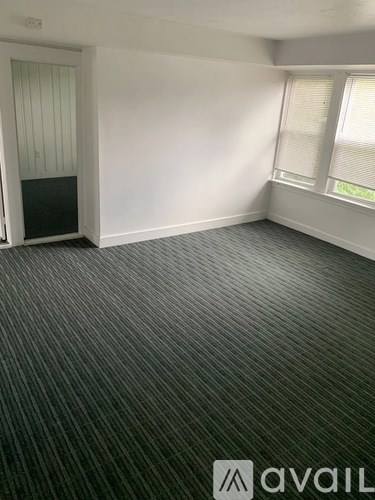 A room with a carpeted floor and a window with blinds.
