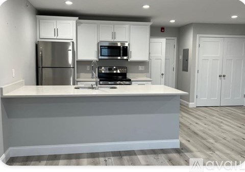 A kitchen with white cabinets and a stainless steel refrigerator.