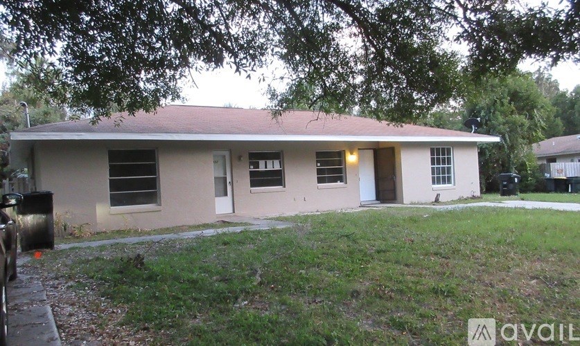 A house with a brown roof and a white door is surrounded by trees.